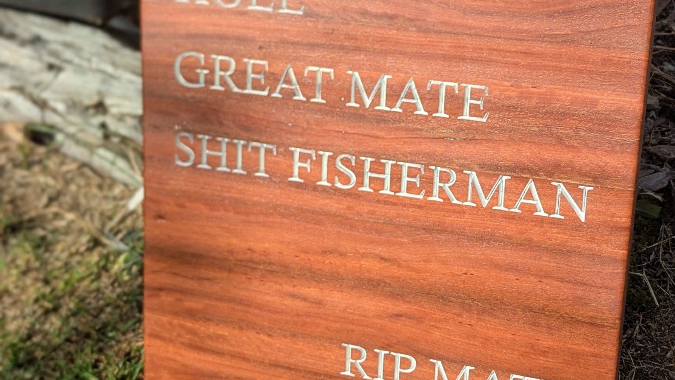 Wooden plaque with engraved text on a grassy background